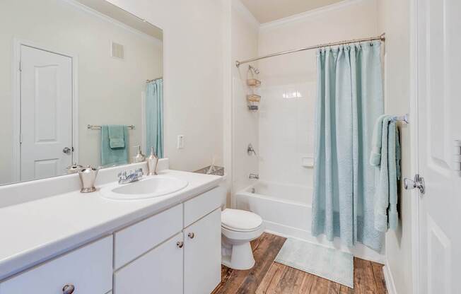 A white bathroom with a blue shower curtain.