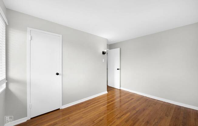 a bedroom with white walls and hardwood floors