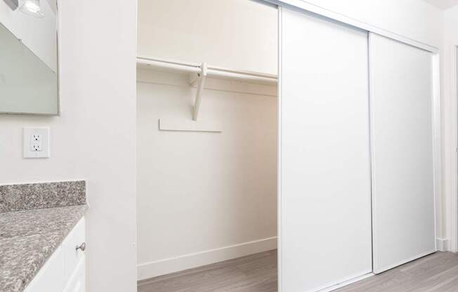 A white closet with a white door and a white shelf.