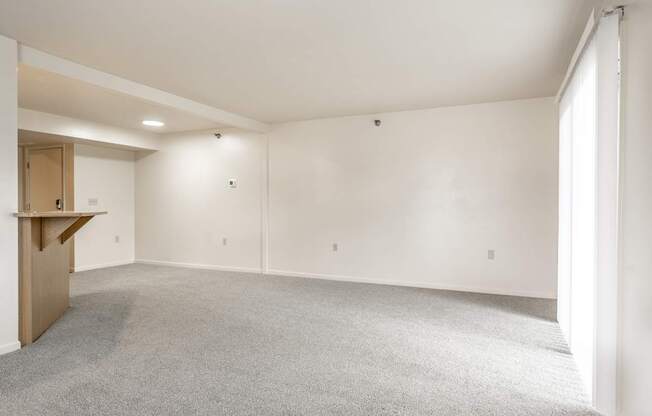 A large, empty room with a carpeted floor and white walls