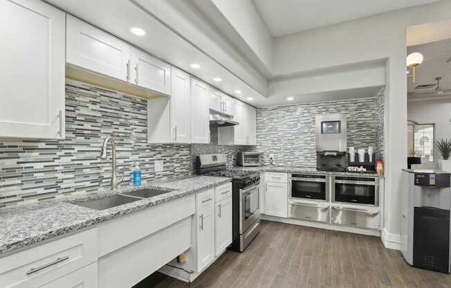A modern kitchen with white cabinets and a stone backsplash.