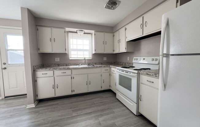 an empty kitchen with white appliances and white cabinets