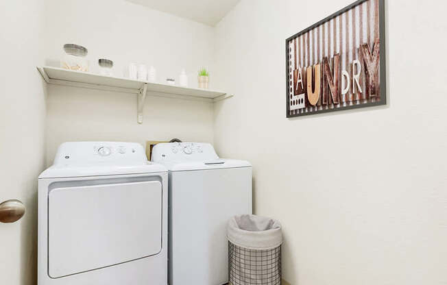 A laundry room with a washer and dryer and a shelf at Tanglewood Apartments, Oak Creek