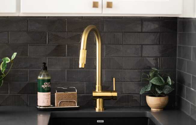 a kitchen sink with a gold faucet and white cabinets