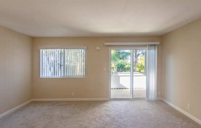 an empty living room with sliding glass doors to a patio