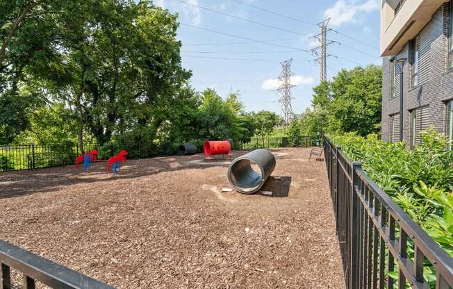 A playground with red and blue slides and a large grey tube.