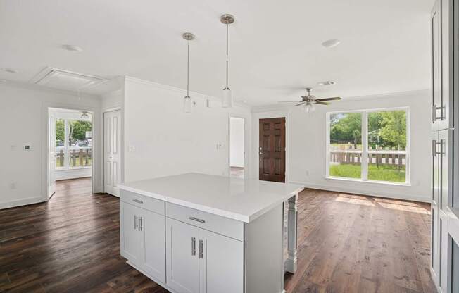 A kitchen with white cabinets and a wooden floor.