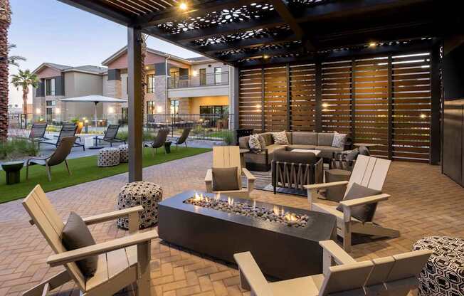 A patio with a fire pit and chairs.