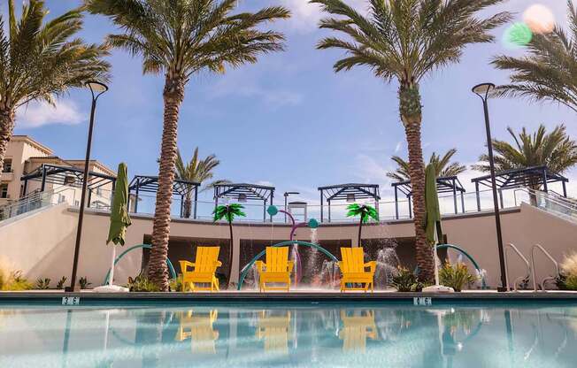 A pool surrounded by palm trees and yellow chairs.