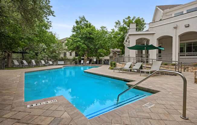 A swimming pool surrounded by trees and a building.