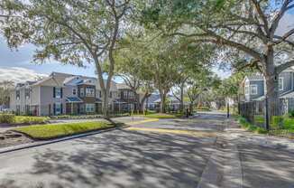 A street view of a residential area with houses on both sides and a tree-lined street.