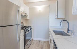 a kitchen with white cabinets and a stainless steel refrigerator  at The Preston at Hillsdale, San Mateo, CA