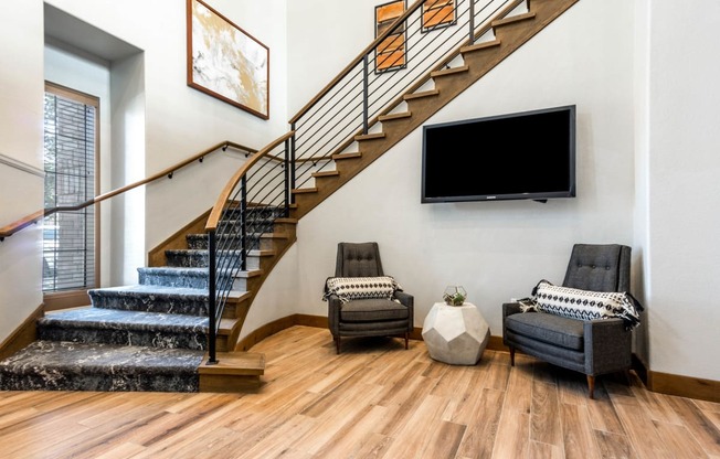 a living room with a staircase and a tv on the wall at The links at Plum Creek Apartments, Castlerock
