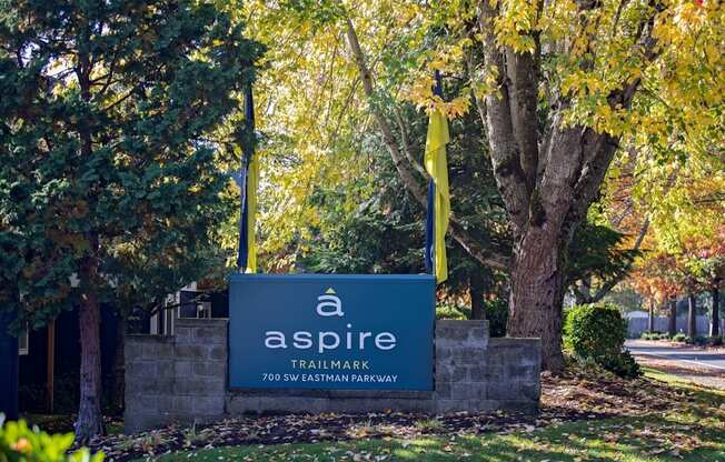 A sign for Aspire Trailmark is shown in front of a tree.