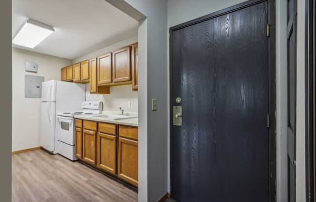 a kitchen with wooden cabinets and white appliances and a black door