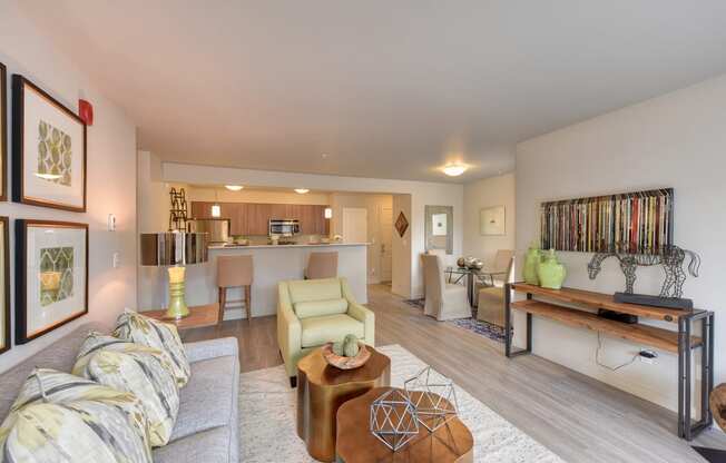 Model Living Room with View of Kitchen, White Sofa, Hardwood Inspired Floor, Lime Chairs, Ornamental Animal and Green Vase on Wood Table