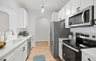 A kitchen with white cabinets and a black stove top oven.