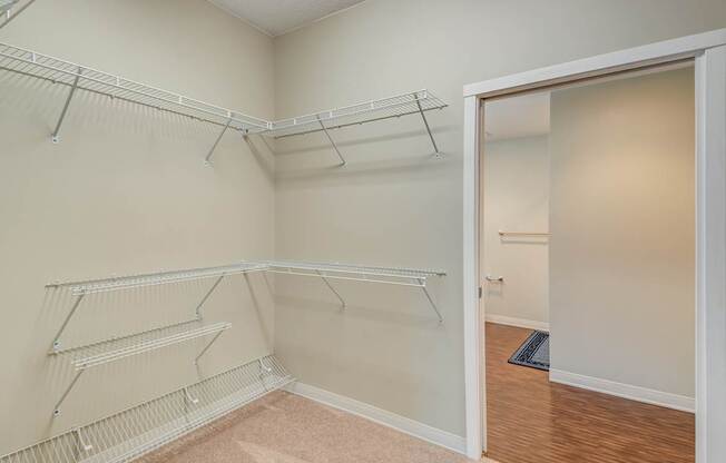 Empty room with white shelves and a doorway leading to another room.
