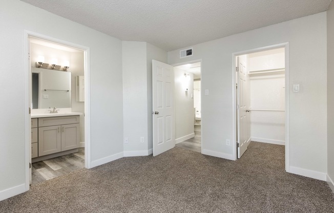 an empty bedroom and bathroom with white doors and carpeting