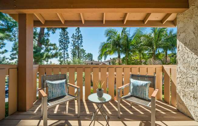 a patio with two chairs and a table on a balcony