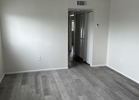 a empty living room with wood flooring and white walls