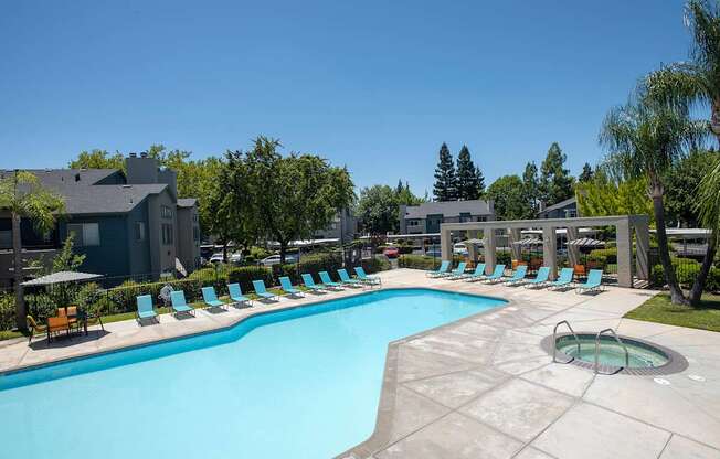 A large swimming pool surrounded by lounge chairs and trees at Autumn Oaks Apartments, Roseville, CA, 95678