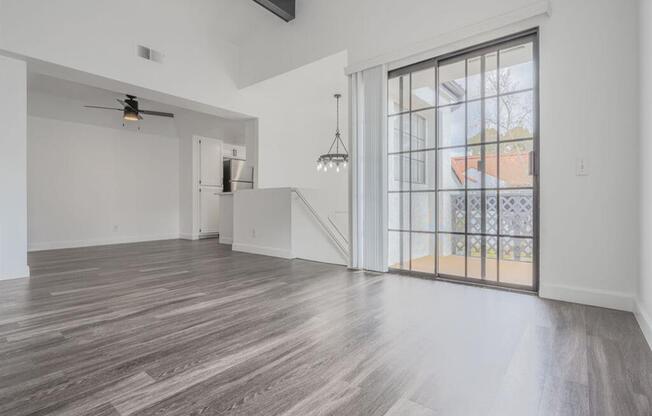 an empty living room with a large window and a staircase  at The Resort at Encinitas Luxury Apartment Homes, California