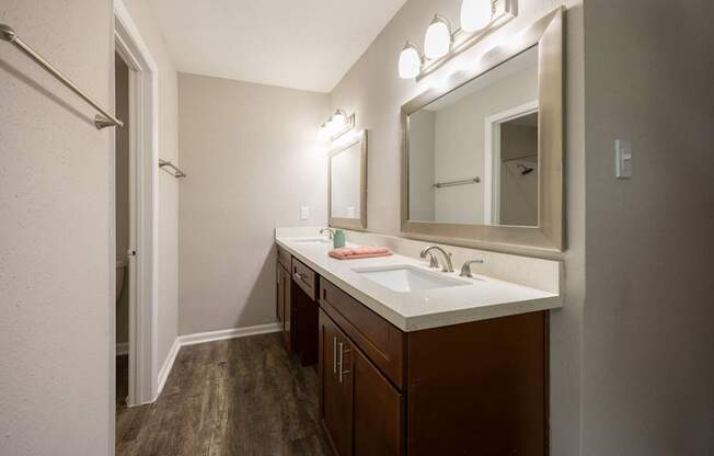 A bathroom with a white sink and brown cabinets.