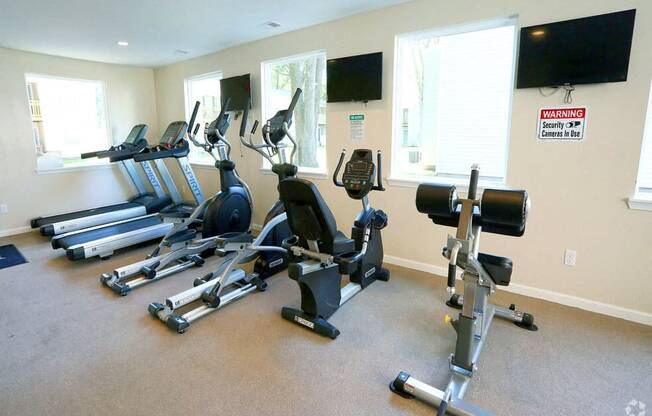 a gym with several pieces of exercise equipment and a tv