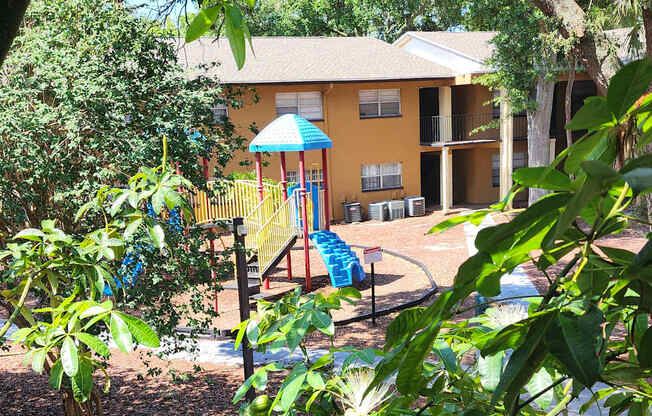A building with a balcony and a tree in the foreground.
