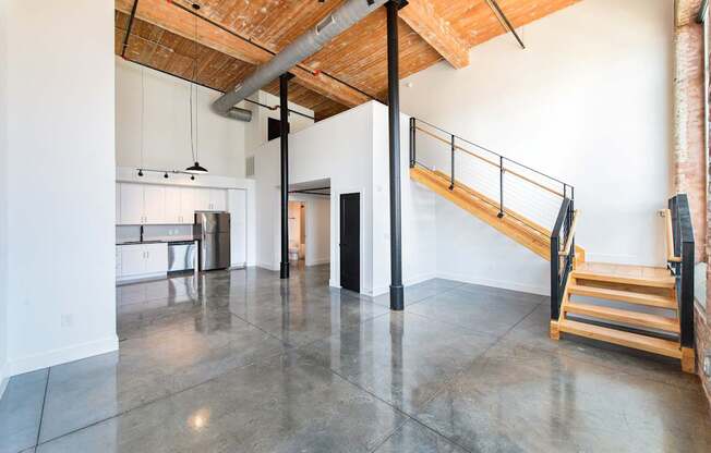 A large open space with a staircase and a kitchen area.