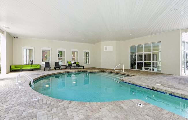 A large indoor swimming pool with a tiled floor and a bench at The Falls Apartments in Raleigh NC