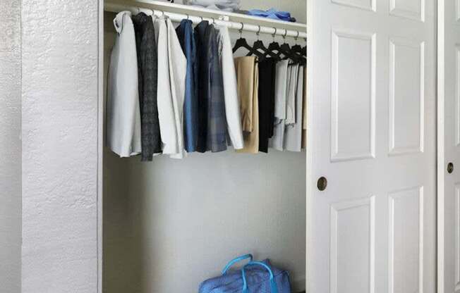 Clothes hanging on a rack in a closet.