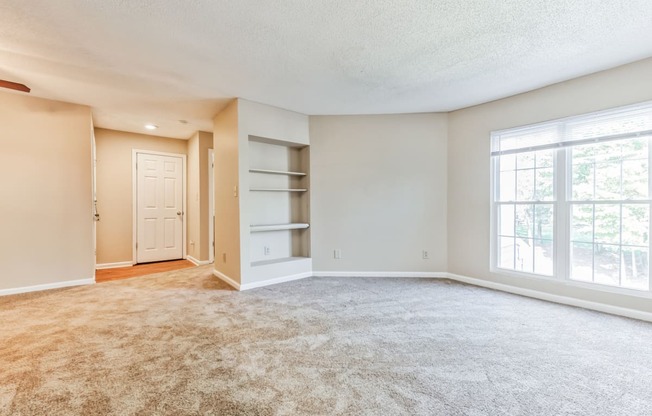 an empty living room with a large window and a closet