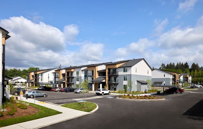 a rendering of an apartment complex with a parking lot in the foreground and buildings in the background