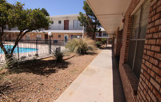 a walkway leading to a pool at the whispering winds apartments in pearland, tx