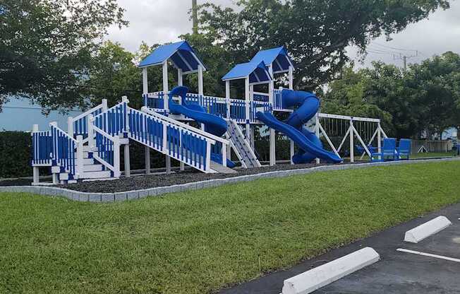 a playground with a blue set of slides in a parking lot