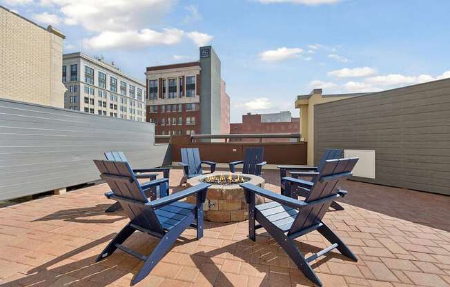 A patio with blue chairs and a fire pit.