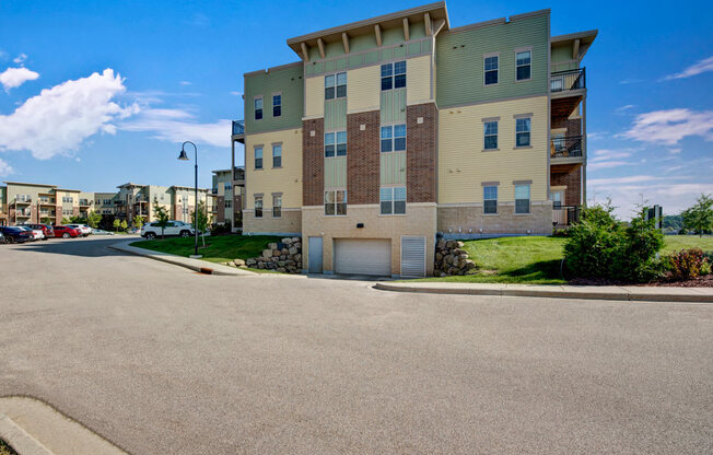 A welcoming exterior building view here at Swan Creek with modern facade, private balconies, manicured landscaping, and bright blue sky, creating a clean, inviting, and well-maintained community setting.