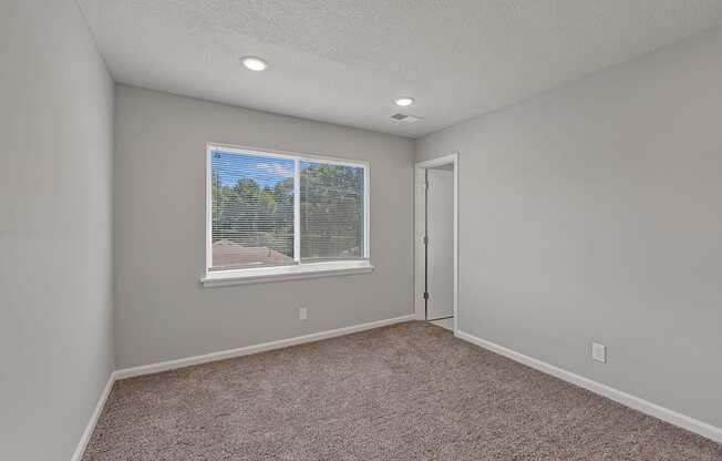 an empty room with a window and carpet