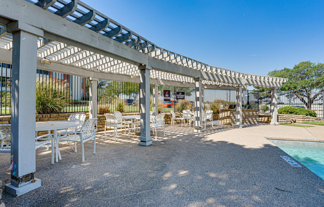 a covered patio with tables and chairs next to a pool