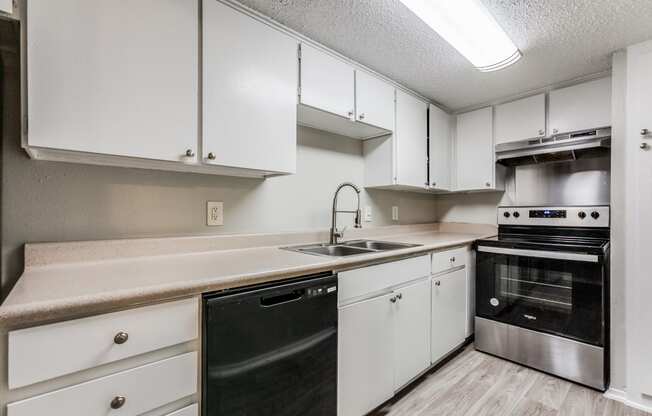 an empty kitchen with white cabinets and black appliances