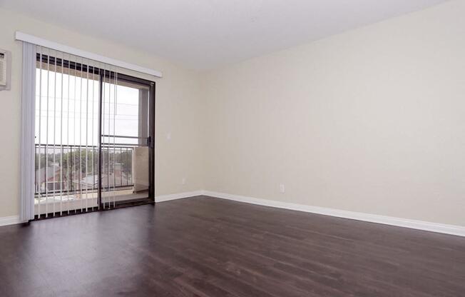 an empty living room with wood floors and a sliding glass door