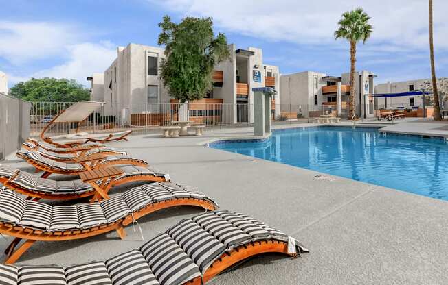 a pool with lounge chairs and palm trees in the background