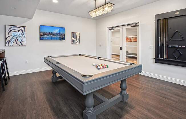 A pool table in a room with a television and picture frames on the wall.