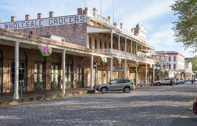 A street view of a Wholesale Grocers store with a green car parked in front.