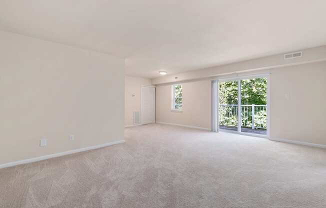 a spacious living room with a sliding glass door leading to a balcony