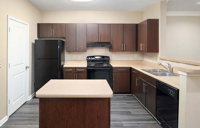 A kitchen with black appliances and brown cabinets.