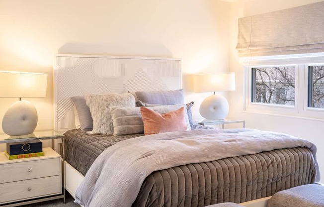 A bedroom with a bed, nightstands, and lamps.