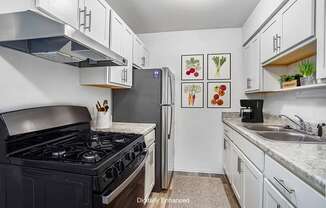 An updated kitchen with a gas stove and white cabinets at Fairlane Apartments, Springfield, Michigan